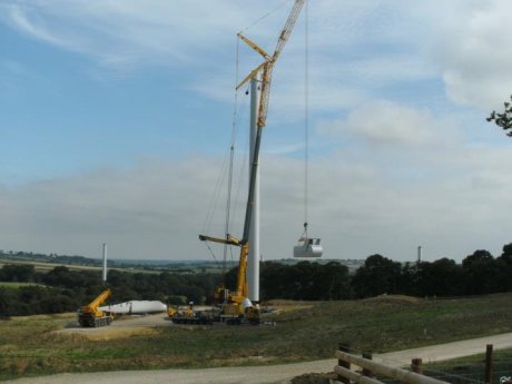 Crane installing a wind turbine on a grassed Truckcell surface
